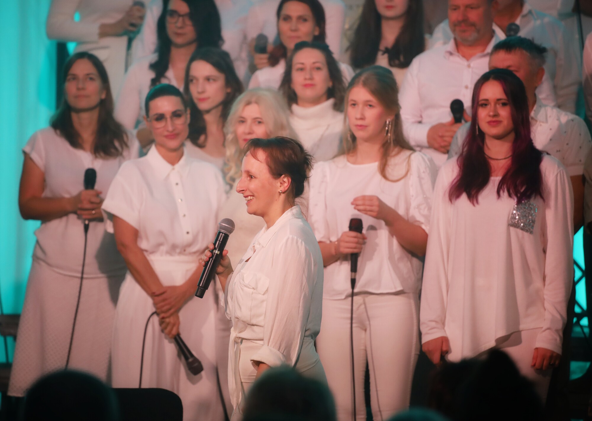 Sbormistryně s mikrofonem před sborem